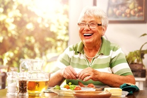 Woman with dentures smiling at dinner table