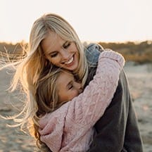 Woman hugging daughter outdoors
