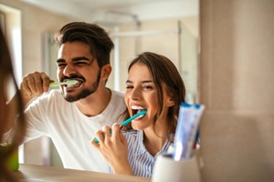 Man and woman brushing their teeth together.