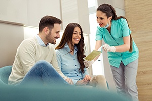 Dental assistant reviewing financial information with smiling couple